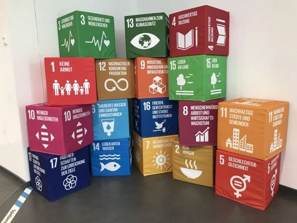 Bunte W&uuml;rfel mit den Symbolen der 17 Nachaltigkeitsziele (SDGs) sind zu einer Gruppe aufgebaut.